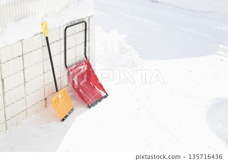 A woman's dump truck and snow shovel leaning against a snow-covered fence A woman's dump truck and snow shovel leaning against a snow-covered fence 135716436