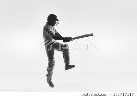 Cricket batsman airborne attacking shot in studio isolated on white. Cricket batsman airborne attacking shot in studio isolated on white. 135717117