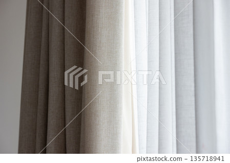A closeup of layered beige and white curtains 135718941