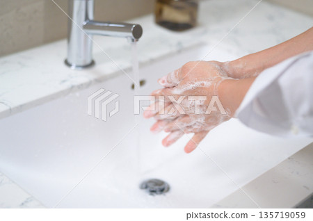 A man washing his hands in the bathroom 135719059