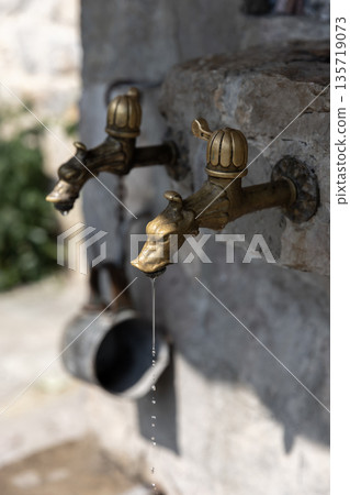 A vintage brass outdoor faucet mounted on a rough stone wall, A vintage brass outdoor faucet mounted on a rough stone wall, 135719073