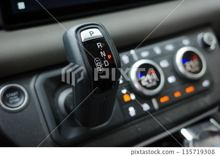 Close-up detail of modern car automatic transmission shifter with gear positions and dashboard controls, vehicle interior and driving technology concept Close-up detail of modern car automatic transmission shifter with gear positions and dashboard controls, vehicle interior and driving technology concept 135719308