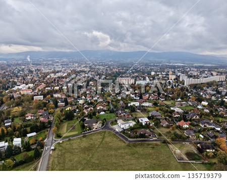 aerial shot capturing peaceful neighborhood scenes amid lush fields and distant urban skyline 135719379