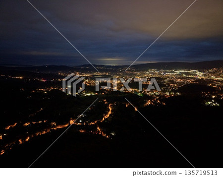 nighttime road scene, serpentine vehicle lights illuminate distant suburban outskirts with soft silhouettes nighttime road scene, serpentine vehicle lights illuminate distant suburban outskirts with soft silhouettes 135719513