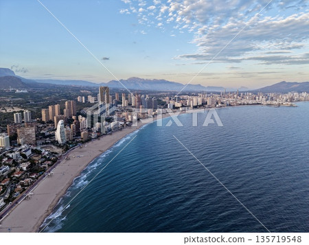 picturesque shoreline featuring highrise structures and generous stretch of golden sands under serene sky 135719548