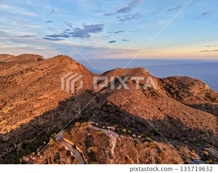 serene hillside surrounded by nature, mighty promontory overlooking tranquil waters beneath glowing sunset serene hillside surrounded by nature, mighty promontory overlooking tranquil waters beneath glowing sunset 135719632