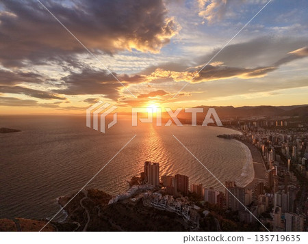 sunset casts striking shadows over serene bay with reflective orange light and urban outlines sunset casts striking shadows over serene bay with reflective orange light and urban outlines 135719635