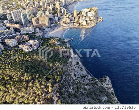 tall cliffs border lush pine covered land, nature and urban landscapes coexist on rugged coastlines 135719636