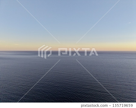 peaceful early morning ocean scene, calm ocean at sunrise with soft colors and reflective surface peaceful early morning ocean scene, calm ocean at sunrise with soft colors and reflective surface 135719659