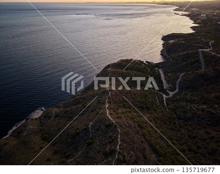 evening seaside trail, sunset along rugged coast offers atmospheric scene perfect for travel features 135719677