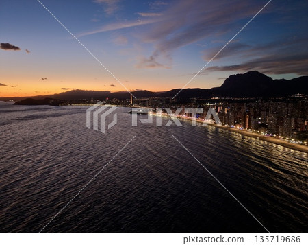 dusk landscape showing luminous cityscape, sunset horizon over sparkling coastal town at nightfall dusk landscape showing luminous cityscape, sunset horizon over sparkling coastal town at nightfall 135719686