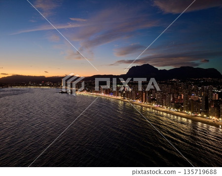 twilight above city highlighting shimmering water reflections and towering structures with vivid sky twilight above city highlighting shimmering water reflections and towering structures with vivid sky 135719688