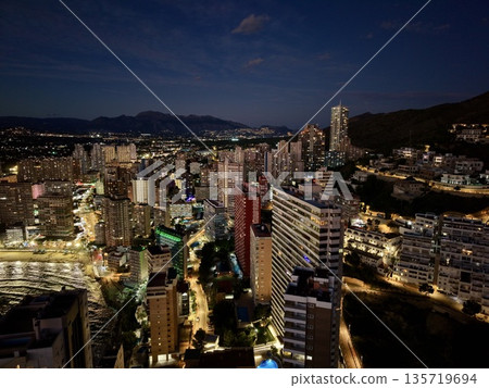 serene sunset over waterfront urban area, calm dusk horizon with twinkling lights and distant mountains serene sunset over waterfront urban area, calm dusk horizon with twinkling lights and distant mountains 135719694