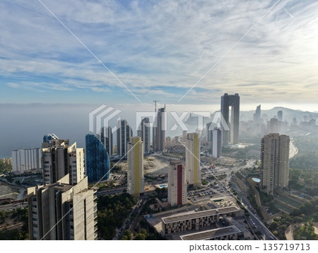 mist surrounds oceanfront cityscape at dawn, serene early morning scene of seafront city and pale mist mist surrounds oceanfront cityscape at dawn, serene early morning scene of seafront city and pale mist 135719713