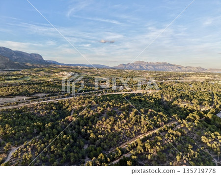 sunlit rugged landscape views, sunshine bathes winding roads and rocky hills in vibrant glow 135719778