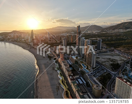 sunrise over harbor with shadows, tower silhouette against vibrant morning sky with textured sand sunrise over harbor with shadows, tower silhouette against vibrant morning sky with textured sand 135719785