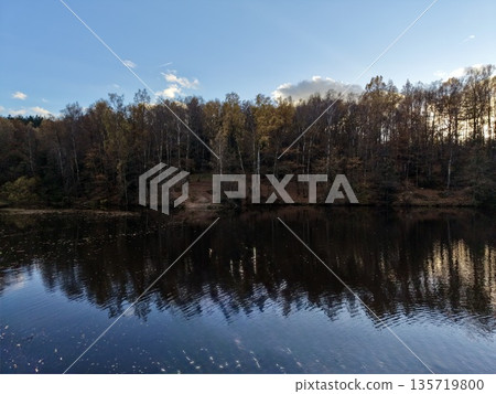 autumn water reflection, rustic landscape capturing fall reflections on peaceful lake with bright sky 135719800