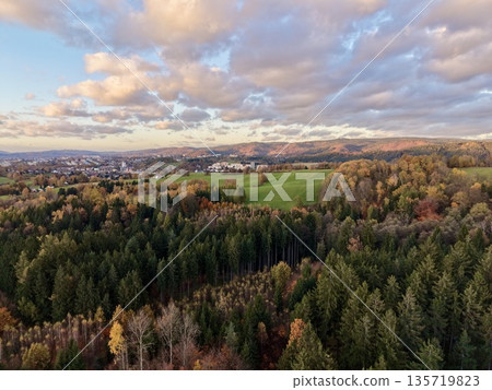vast woodland with village views, rolling hills accentuated by warm sunset and shadow play 135719823