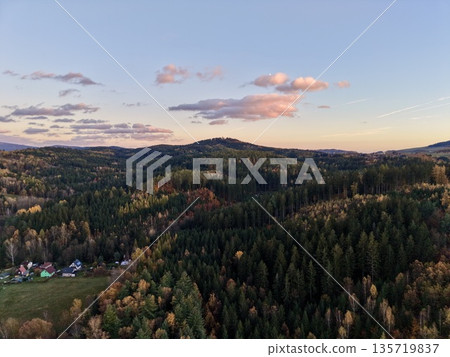 pink sunset landscape, warm pastel glow casts serene ambiance across forested hills and distant slopes 135719837