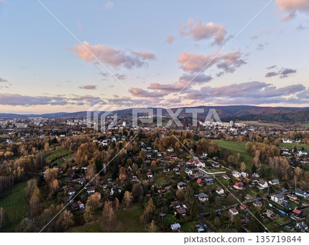 gentle dusk panorama capturing cozy settlement surrounded by rolling hills and soothing light 135719844