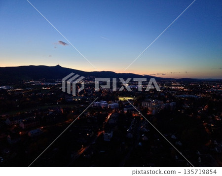 urban horizon illuminated beneath evening sky, dusk paints cityscape with shimmering lights and distant hills 135719854