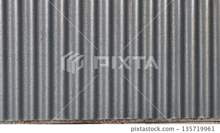 Galvanized metal fence fragment with corrugated wavy shiny silver surface as empty plain bright background texture Galvanized metal fence fragment with corrugated wavy shiny silver surface as empty plain bright background texture 135719961