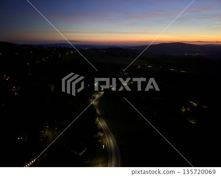bright headlights trace meandering routes, illuminated highways wind through shadowed rural landscapes bright headlights trace meandering routes, illuminated highways wind through shadowed rural landscapes 135720069