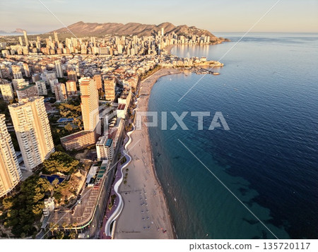 bright coastal scene, sunny seaside with lively activity, vibrant beach area with boats and scenery 135720117