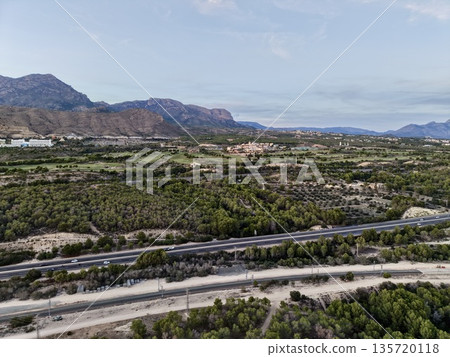 bright valley with winding roadway, tranquil journey along multilane route through scenic landscapes 135720118