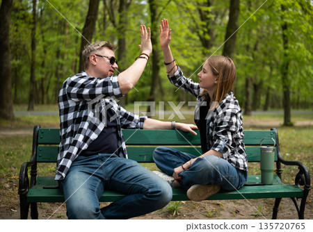 Happy Father And Little Daughter Sit On A Bench Giving A High Five In Family Look 135720765