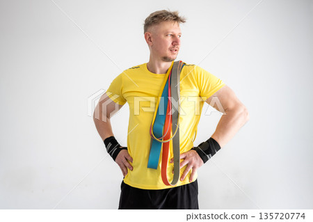 Sporty Man Holding Resistance Rubber Bands For Home Training On A White Background Sporty Man Holding Resistance Rubber Bands For Home Training On A White Background 135720774