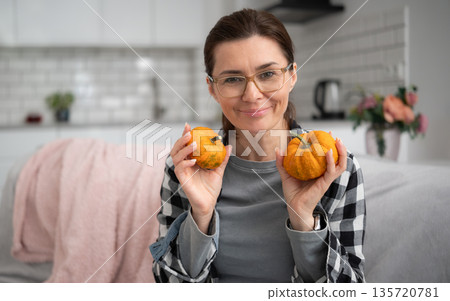Girl In Glasses Holding Small Orange Pumpkins And Writing Notes In Notebook 135720781