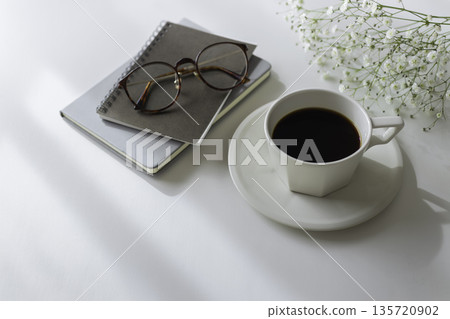 白色桌面上擺放著咖啡、筆記本、眼鏡和滿天星。極簡主義工作空間。留有文字空間。 135720902