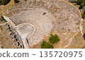Aerial view of an ancient stone amphitheater in Bodrum, Turkey. Historic archaeological landmark with semicircular seating and stage, filmed from above in daylight.  135720975