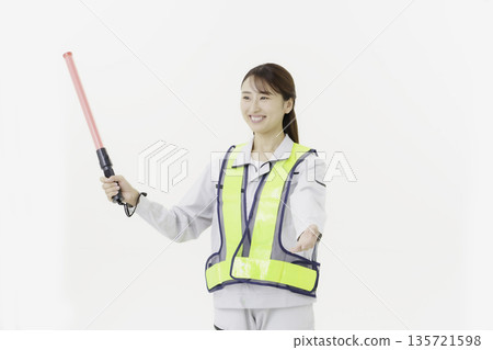 A young Japanese woman wearing work clothes with a safety belt and holding an emergency exit sign on a white background A young Japanese woman wearing work clothes with a safety belt and holding an emergency exit sign on a white background 135721598