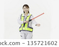 A young Japanese woman wearing work clothes with a safety belt and holding an emergency exit sign on a white background 135721602