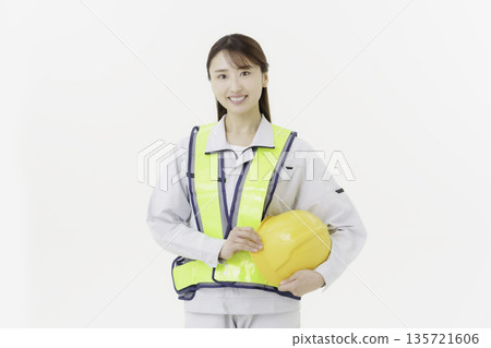 一位年輕的日本女性身穿工作服，繫著安全帶，戴著安全帽，背景為白色。 135721606
