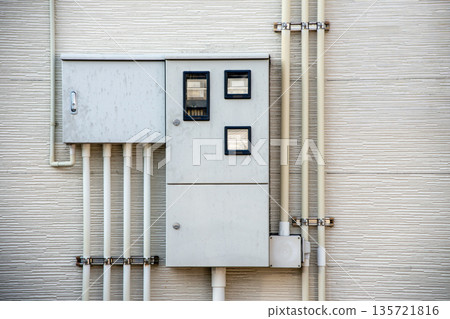 Electric meter box and piping on the exterior wall of an apartment building Electric meter box and piping on the exterior wall of an apartment building 135721816