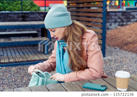 A woman sits in a gazebo in the courtyard of a house A woman sits in a gazebo in the courtyard of a house 135722136