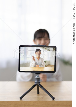A young woman live streaming using a tablet A young woman live streaming using a tablet 135723536