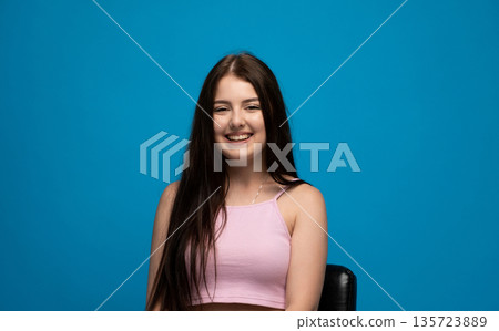 Smiling young woman with long hair against blue background, positive emotion portrait and friendly mood concept Smiling young woman with long hair against blue background, positive emotion portrait and friendly mood concept 135723889