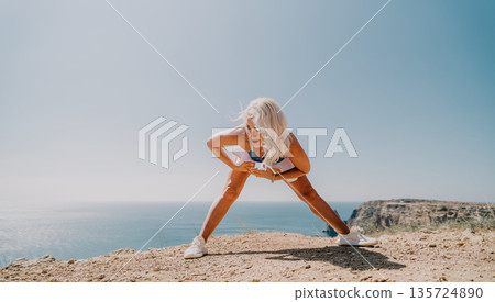 Woman Stretching on Cliffside Overlooking Ocean Woman Stretching on Cliffside Overlooking Ocean 135724890