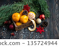 Orange mandarins in wooden box with fir apple, red balls, snowflakes on green fir branch background. Christmas card. Happy new year and merry christmas. High quality photo 135724944
