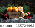 Orange mandarins in wooden box with fir apple, red balls, snowflakes on green fir branch background. Christmas card. Happy new year and merry christmas. High quality photo 135724968