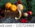 Orange mandarins in wooden box with fir apple, red balls, snowflakes on green fir branch background. Christmas card. Happy new year and merry christmas. High quality photo 135724969