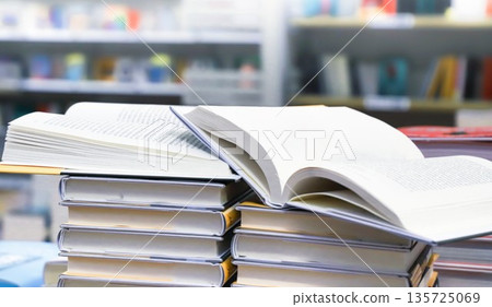 stack of books, close up. Open book on the table in library. Back to school concept. Open book on table with blur bookshelf background stack of books, close up. Open book on the table in library. Back to school concept. Open book on table with blur bookshelf background 135725069