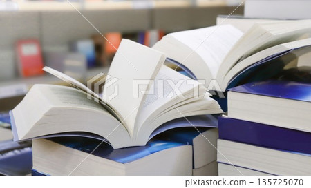 stack of books, close up. Open book on the table in library. Back to school concept. Open book on table with blur bookshelf background stack of books, close up. Open book on the table in library. Back to school concept. Open book on table with blur bookshelf background 135725070