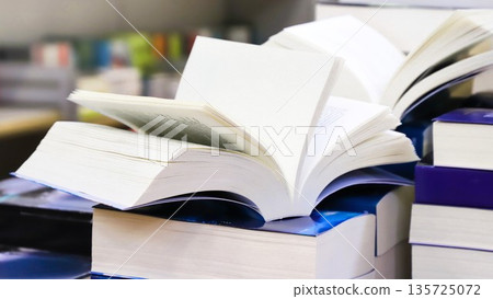 stack of books, close up. Open book on the table in library. Back to school concept. Open book on table with blur bookshelf background 135725072