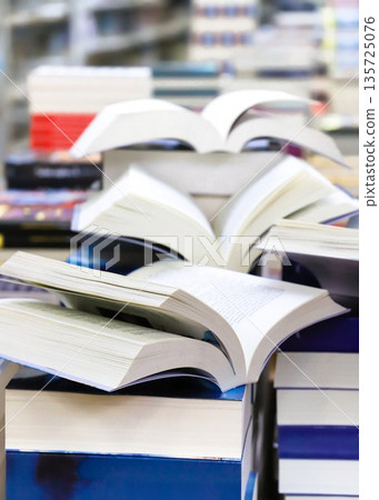 stack of books, close up. Open book on the table in library. Back to school concept. Open book on table with blur bookshelf background stack of books, close up. Open book on the table in library. Back to school concept. Open book on table with blur bookshelf background 135725076