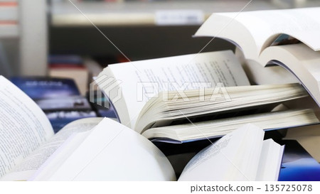 stack of books, close up. Open book on the table in library. Back to school concept. Open book on table with blur bookshelf background stack of books, close up. Open book on the table in library. Back to school concept. Open book on table with blur bookshelf background 135725078